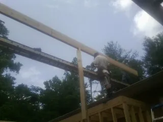 Carpenter setting a ridge beam over a new addition frame — Ice Dam Removal by Roofing Brothers in Clawson