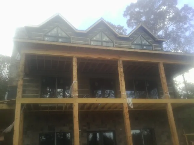 Dormers and porch framing on a large log home under construction — Roof Coating work by our crew in Clawson