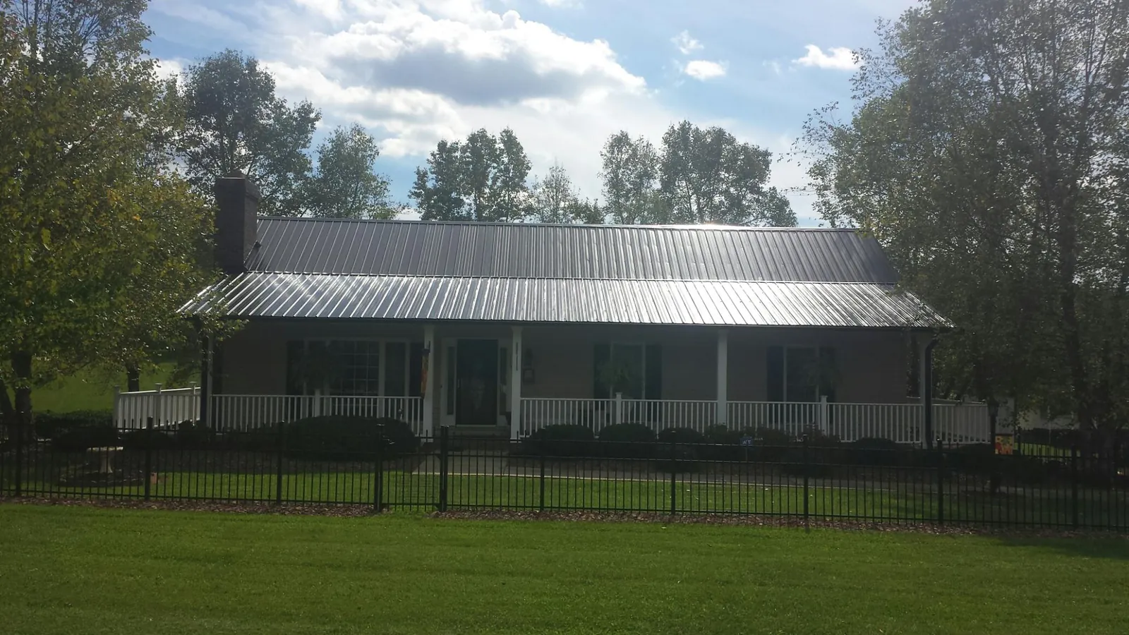 Gray metal roof on a brick ranch with a full width front porch — Gutter Guard Installation work by our crew in Clawson