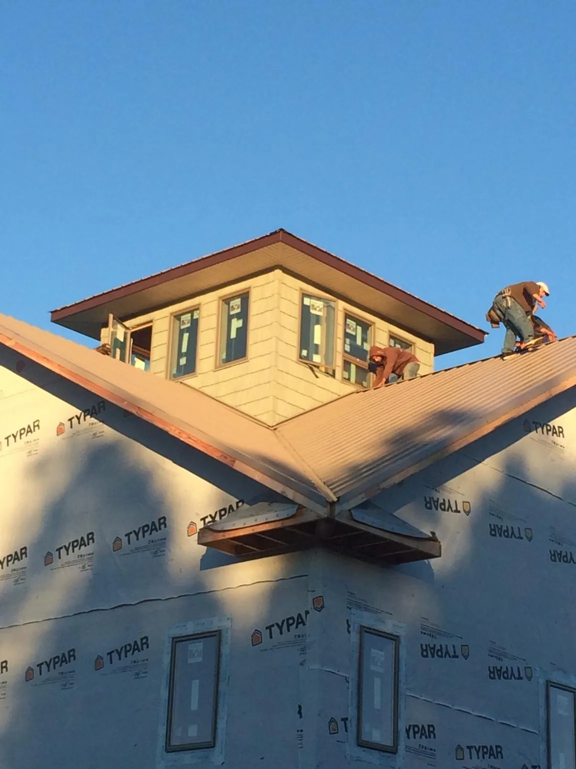 Roofers working around a rooftop cupola on a new metal roof at sunset — Roof Waterproofing in Clawson by Roofing Brothers